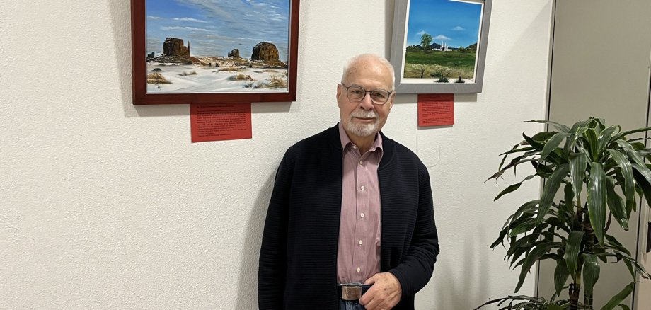 Die Bilder von Hartmut Schulz sind noch bis September im Foyer der Stadtverwaltung zu sehen. Das Foto zeigt den Maler Hartmut Schulz vor zwei seiner Bilder im Foyer.