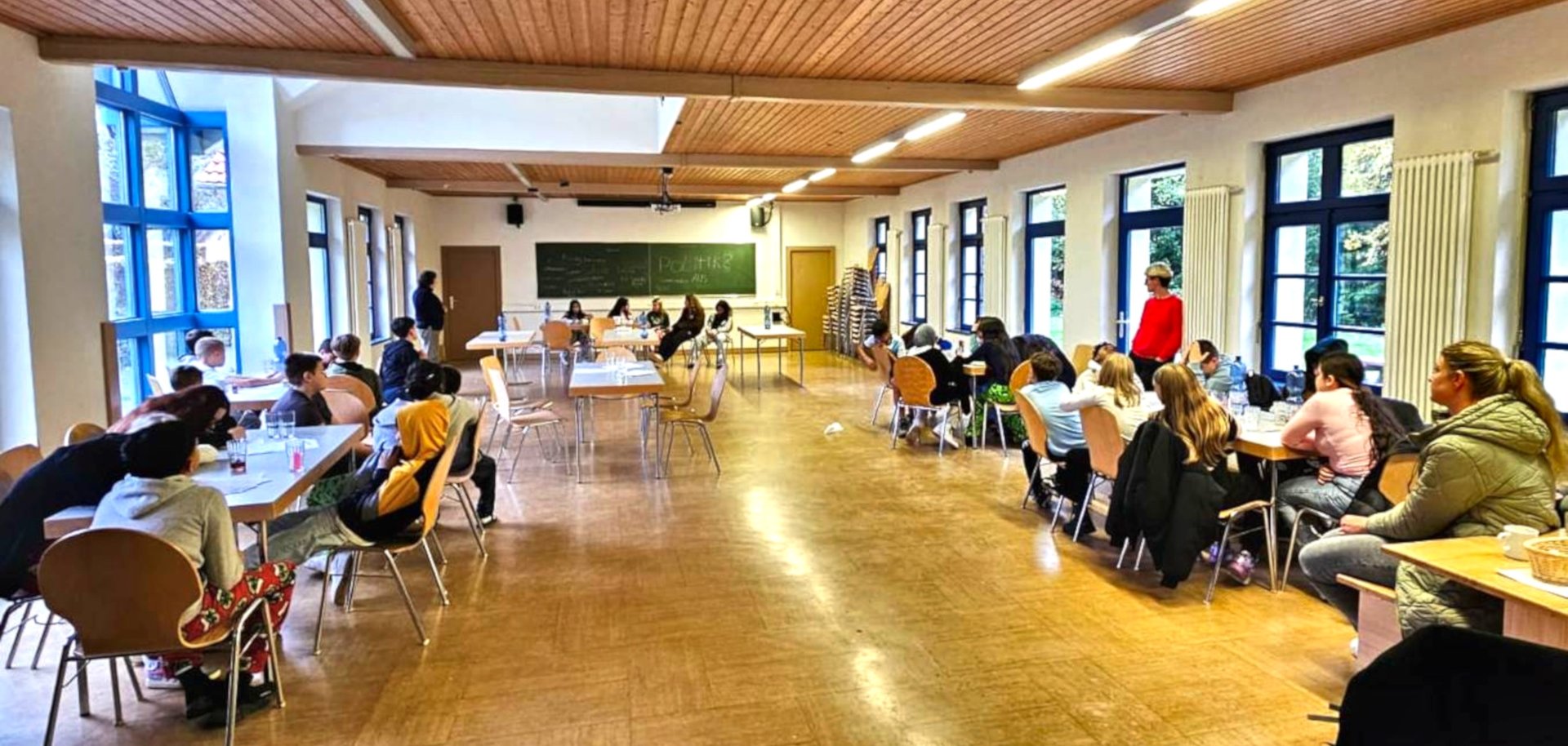 Das Foto zeigt einen Blick in den Schulungsraum, in dem etliche Schülerinnen und Schüler an Tischen vor einer Tafel sitzen.